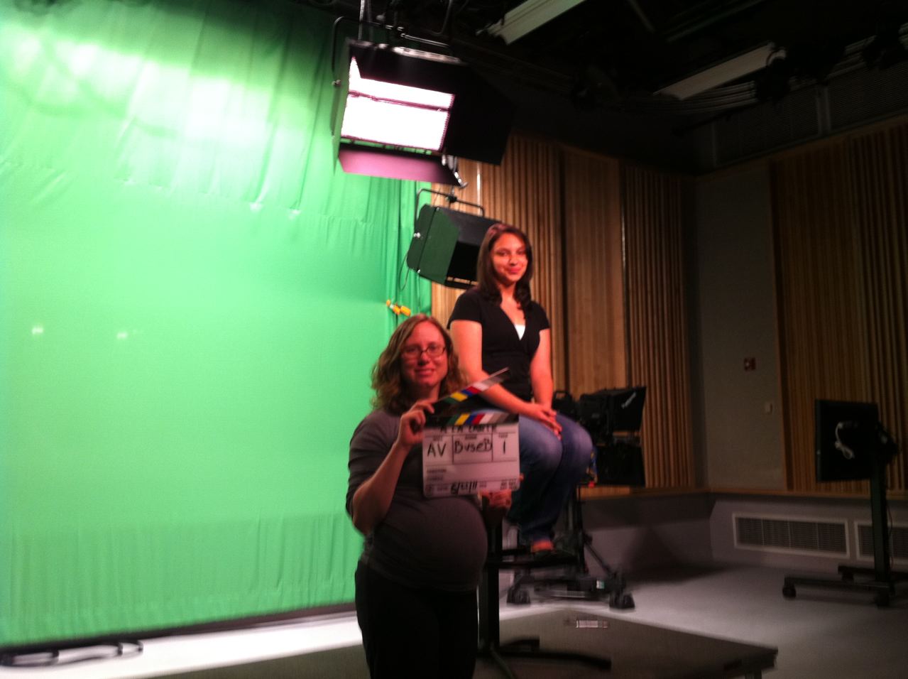 Allie Verbovetskaya (Instructional Technologies Librarian; seated) and Jennifer King (Science Librarian) posing in front of the green screen before 'Action!' is called